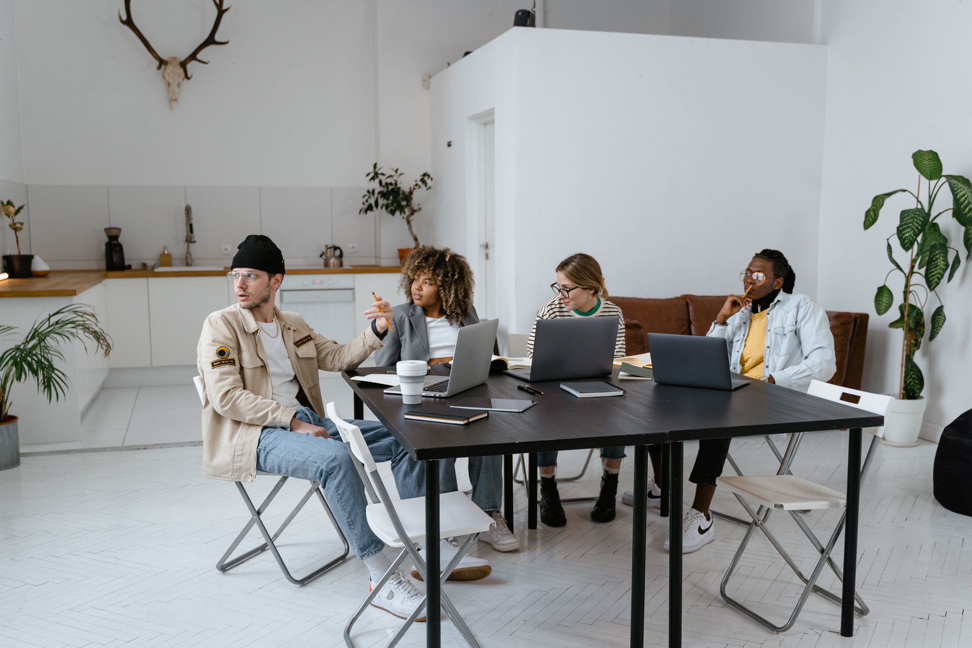 Members gathered around the communal work table beside the open kitchen and lounge area at Northline Collective, laptops and coffee in front of them.